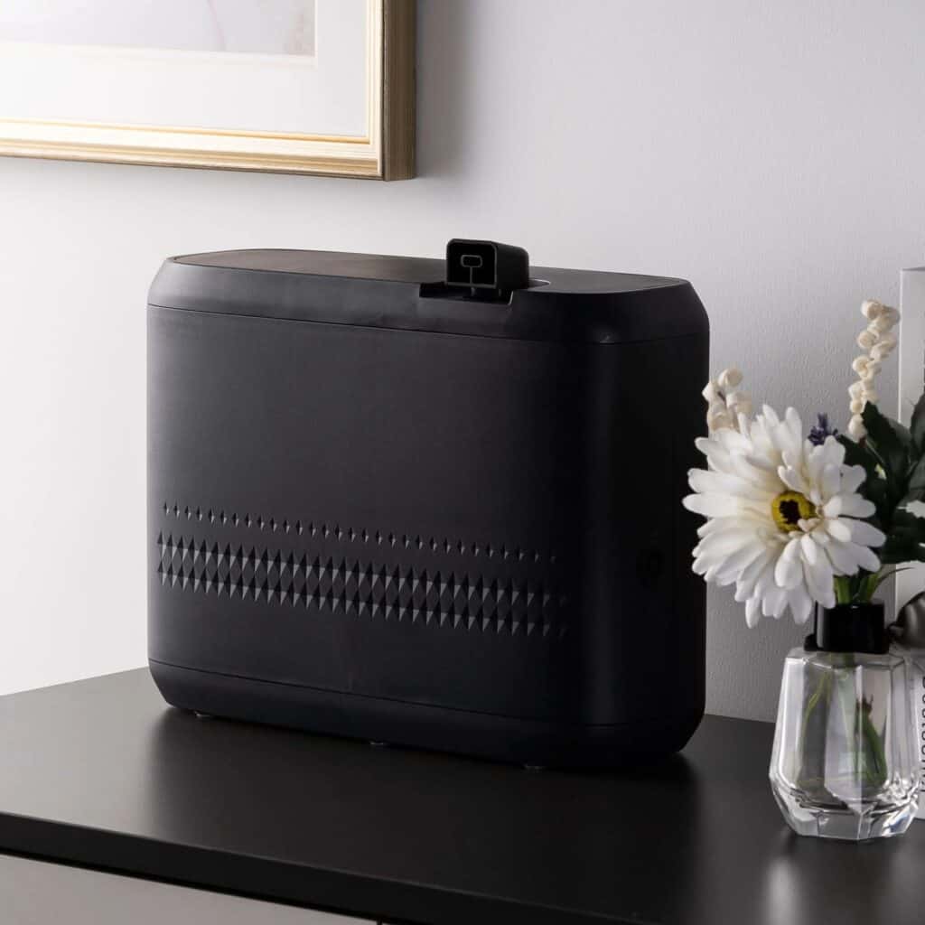 Sleek black aroma diffuser on a modern table with a glass vase of white flowers, showcasing elegant scent marketing solutions for creating inviting atmospheres in homes and businesses.